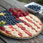 4th of July fruit pizza topped with strawberries, blueberries, and banana slices arranged like the American flag
